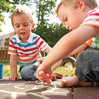 Two small children drawing with chalk on a path