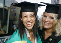 Two graduating students next to a tram