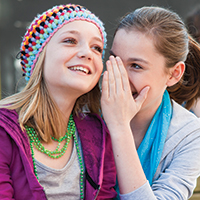 Two girls, one is whispering to the other.